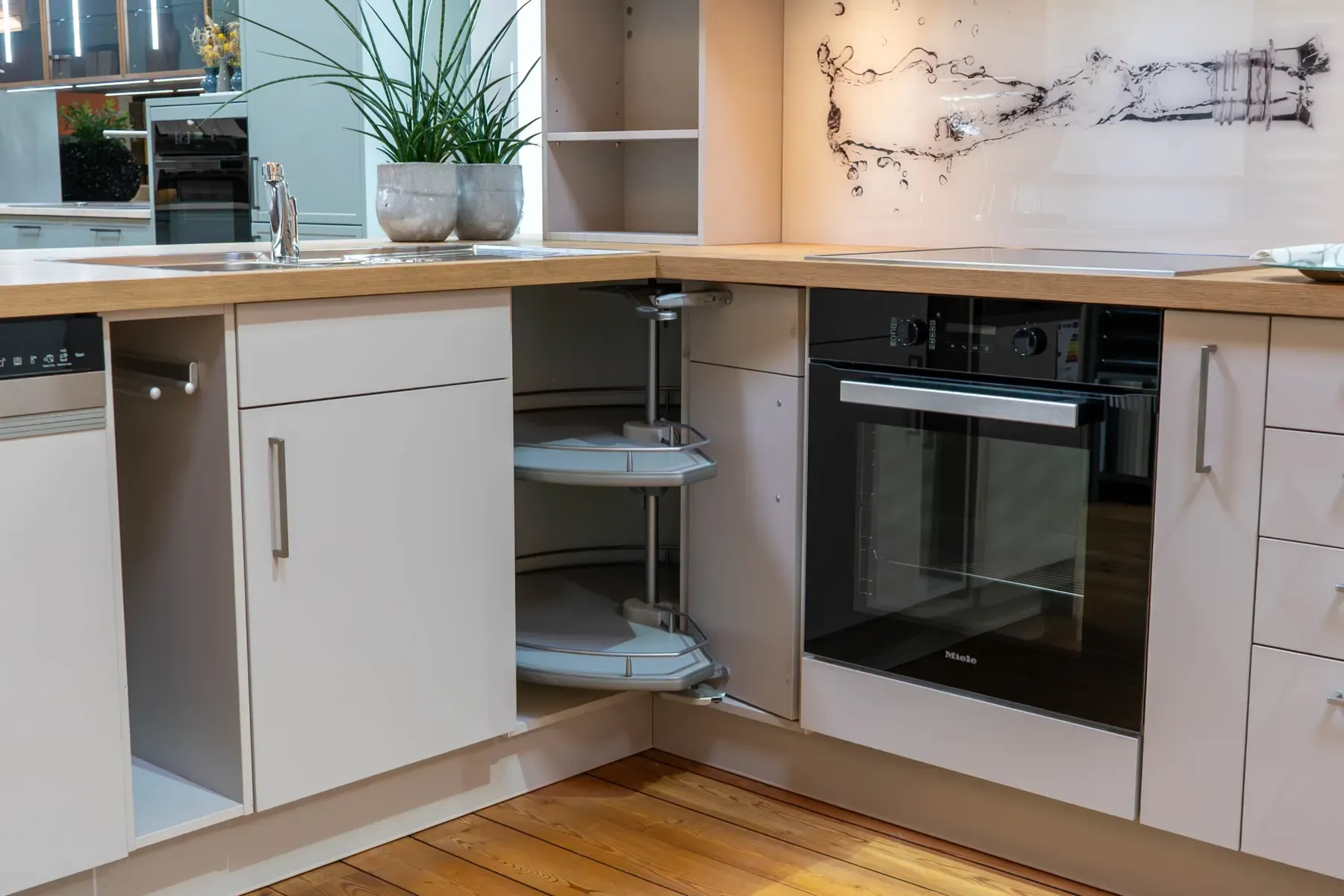 Helle Einbauküche in Weiß mit Holz-Arbeitsplatte, ausgeschwenktem Eckschrank-Karussell und schwarzem Miele-Einbaubackofen